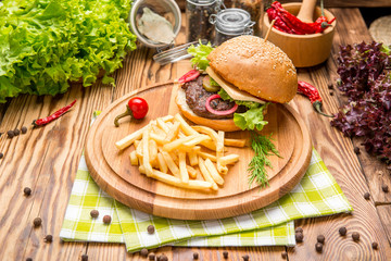 Fast food dish top view. Meat burger in craft paper and potato chips. Take away composition.