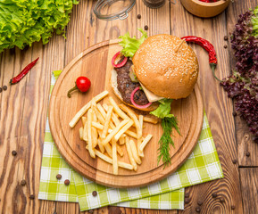 Fast food dish top view. Meat burger in craft paper and potato chips. Take away composition.
