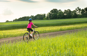 girl on a bicycle in rural landscape