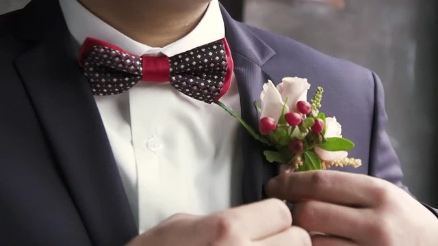 The groom straightens the buttonhole, wedding