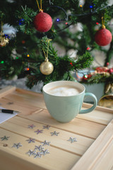 Obraz na płótnie Canvas Cup of coffee on the wooden box next to the xmas tree