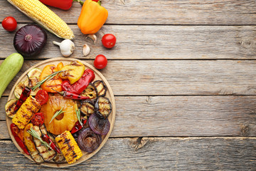 Grilled vegetable on brown cutting board with garlic, onion and corn