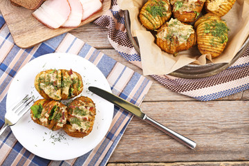 Baked potato with cheese and bacon in plate on wooden table
