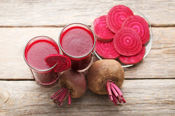 Fresh beets juice in glass on grey wooden table