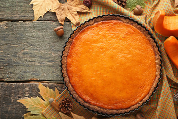 Pumpkin tart with napkin, cone and acorns on wooden table