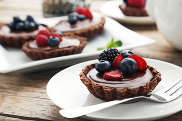 Chocolate tartlets with berries on grey wooden table
