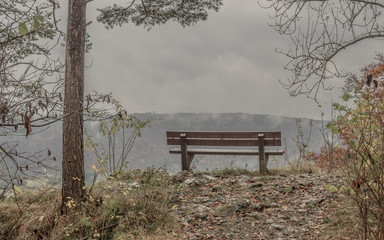 bench with view into a valley on a rainy day