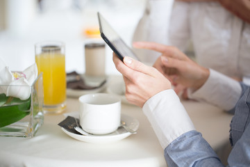 Women typing on a table while having coffee and juice