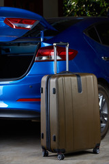 One suitcase stand next to car trunk