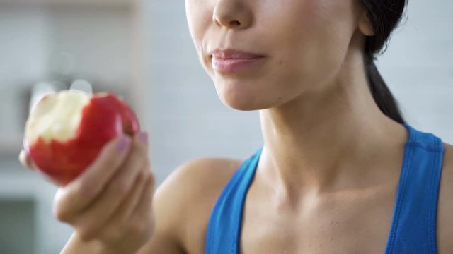 Girl eating apple replenishing her body with vitamins after grueling workout