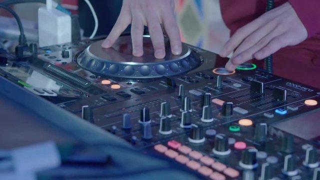 Male DJ play the music on the mixing console in the nightclub, closeup slow motion shot.