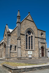 Fototapeta na wymiar Albany WA, Australia - November 23, 2009: Scots Church part of Uniting church in Australia. Gray and Brown stone building with spire against solid blue sky on Duke Street.