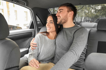 Happy young couple on back seat of taxi car