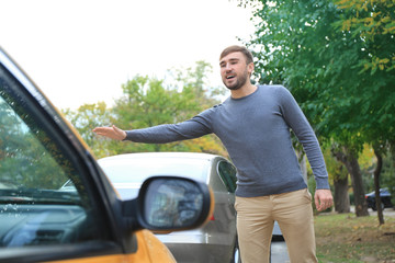 Young man catching taxi on city street