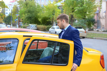 Young businessman getting into taxi car