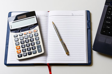 Blank notebook with pen and laptop and calculator on the desk