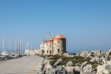 Fototapeta na wymiar Mandhraki Harbor, the yacht and ferry harbour with windmills in the city of Rhodes in Greece