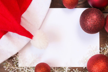 Christmas decoration decorations, bows, ribbons, fir branches, Christmas balls on a wooden background with copy space for text, messages on white sheet, festive mood and atmosphere