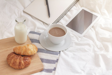 Simple workspace or coffee break in morning. cup of hot coffee, croissant and book on working table in the morning.
