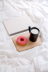 moring with dessert and coffee. Cake donuts with a cup of milk on bed.