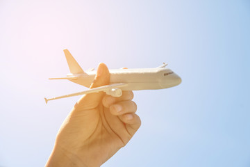 Airplane model in hand on sunny sky. Concepts of travel.