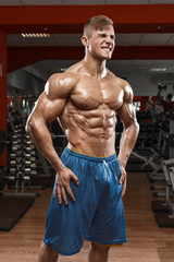 Fototapeta na wymiar Muscular man showing muscles in gym. Strong male naked torso abs, working out