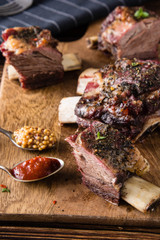 Delicious barbecued ribs seasoned with a spicy basting sauce and served with chopped fresh vegetables on an old rustic wooden chopping board.