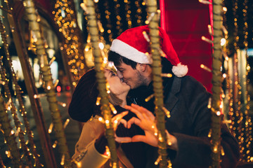Beautiful young couple in love enjoying Christmas or New Year night on a city street. 