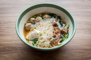 noodle soup meat ball, boil pork and tofu on the wood table and chilli sauce