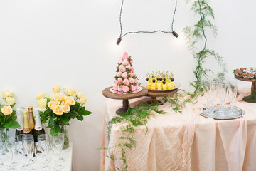 wedding, celebration, treatment concept. there are few tables that are perfectly decorated with flowers and lights and served with bottles of champagne, glasses and dessert