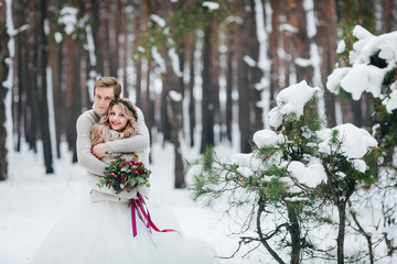 Stylish newlyweds are embracing in the winter forest. Winter wedding. Artwork. - 183107163