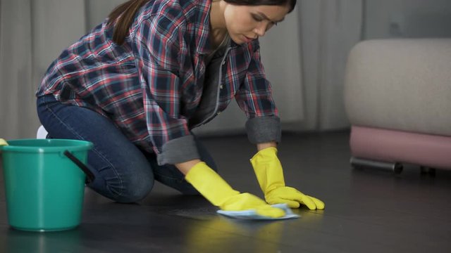 Woman upset with poorly polished floor and stains on wood parquet, cleaning