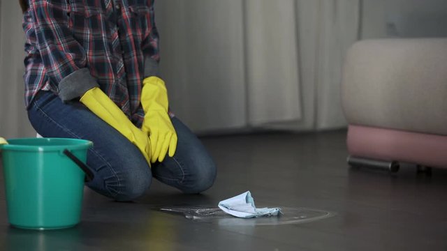 Lady trying to get rid of stains on floor with special remover, polishing