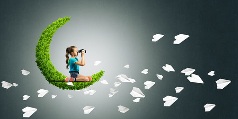 Concept of careless happy childhood with girl on green moon
