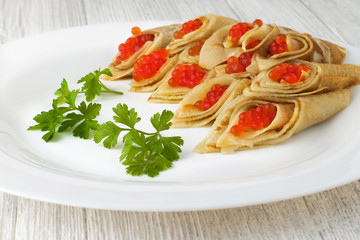 Red caviar and rolls of pancakes.