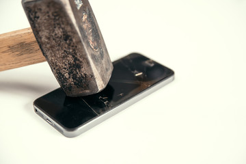 Big hammer breaks the screen of a modern smartphone. Broken glass screen of mobile phone. Crash of...