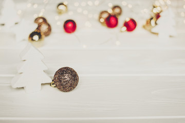 christmas. simple ornaments and christmas trees and stars on white wood with lights in background, space for text. seasonal greetings. happy holidays. xmas gift. holiday celebration
