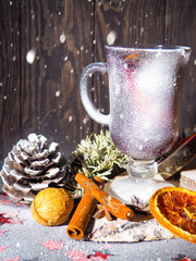 Christmas mulled wine with spices in glasswith plaid and snow on a christmas tree on dark background, The glass cup of hot winter drink