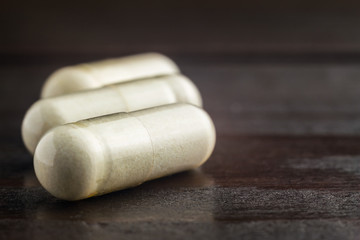 Fototapeta na wymiar White capsules of glucosamine chondroitin, healthy supplement pills on wooden table, macro image
