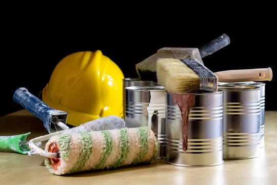 helmet and paint can. The tin is based on a paintbrush for painting walls. Painting tools and working clothes on a wooden table.