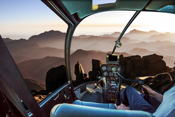 Helicopter cockpit with pilot arm and control console inside the cabin in aerial view of the holy summit of Mount Sinai, Aka Jebel Musa, 2285 meters, at sunrise, Sinai Peninsula in Egypt.