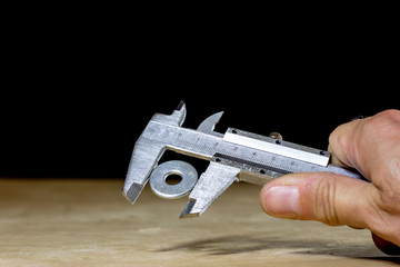 Old good caliper in hand while measuring the abdomen. Wooden table,