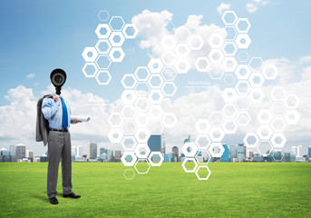 Camera headed man standing on green grass against modern cityscape