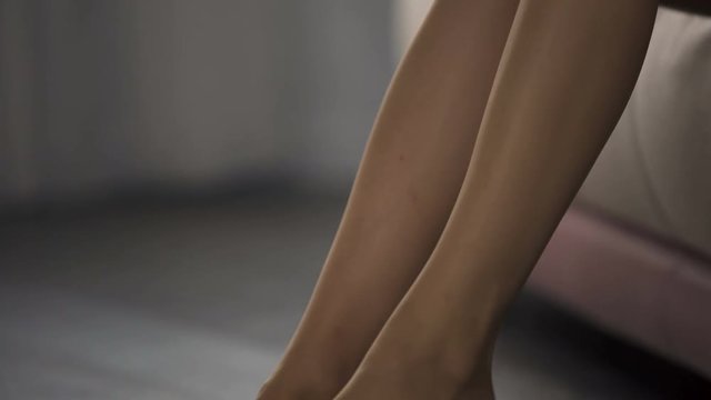 Slim woman quietly dressing nylon pantyhose on her slim legs, start of day