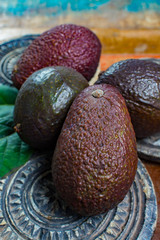 Healthy vegetarian food – green ripe avocado, new harvest, with leaves on stone plates with ornament