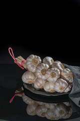 String of french pink garlic on old tin plate on black background