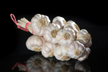 String of french pink garlic on old tin plate on black background