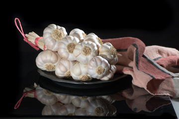 String of french pink garlic on old tin plate on black background