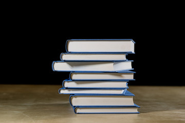 Heap of books reading on a wooden table. Beside lies . Black background.