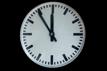 old analog clock showing five to twelve isolated on black background